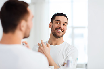 Image showing man with perfume looking to mirror at bathroom