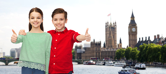 Image showing happy boy and girl showing thumbs up over london