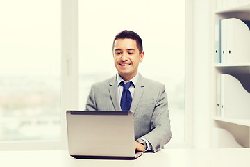 Image showing happy businessman working with laptop in office