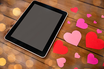 Image showing close up of tablet pc and hearts on wood