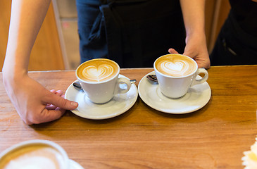 Image showing close up of hands with latte art in coffee cup