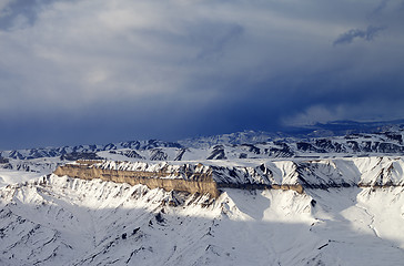 Image showing Winter mountains at sun evening and gray storm clouds