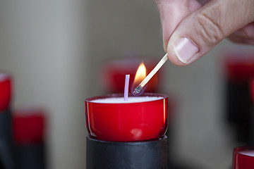 Image showing Female mature woman burning candle light in church