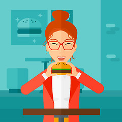 Image showing Woman eating hamburger. 