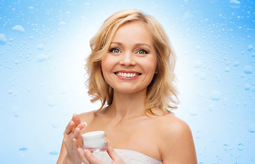 Image showing happy middle aged woman with moisturizing cream