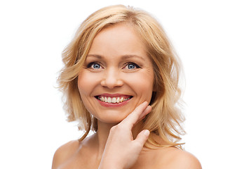 Image showing smiling woman with bare shoulders touching face