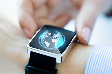 Image showing close up of hand with globe hologram on smartwatch