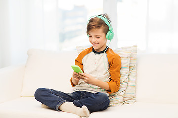 Image showing happy boy with smartphone and headphones at home