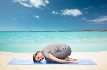 Image showing happy woman making yoga in child pose on beach 