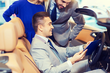 Image showing happy couple with car dealer in auto show or salon