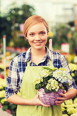 Image showing happy woman holding flowers in greenhouse