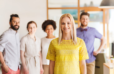 Image showing happy young woman over creative team in office