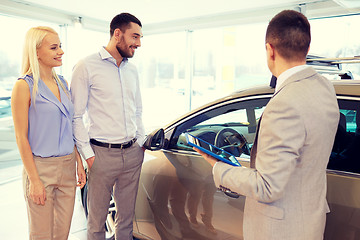 Image showing happy couple with car dealer in auto show or salon