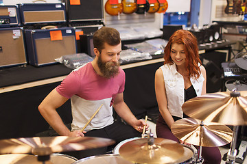 Image showing happy man and woman playing cymbals at music store