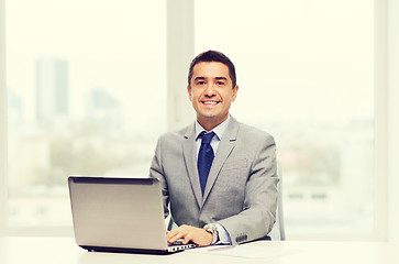 Image showing smiling businessman with laptop and papers