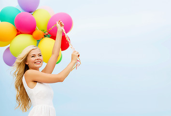 Image showing smiling woman with colorful balloons outside