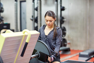 Image showing young woman adjusting leg press machine in gym