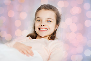 Image showing happy smiling girl lying awake in bed at home