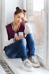 Image showing sad pretty teenage girl with smartphone texting