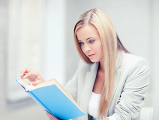 Image showing young woman reading book at school