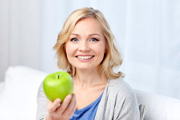 Image showing happy middle aged woman with green apple at home