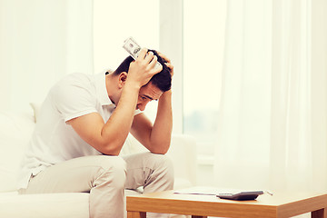 Image showing man with money and calculator at home