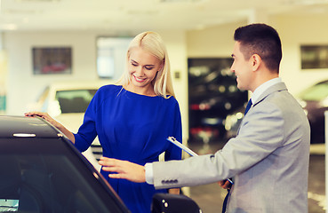 Image showing happy woman with car dealer in auto show or salon