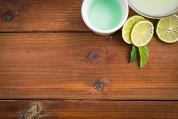 Image showing close up of body lotion, cream and limes on wood