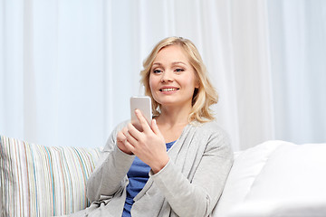 Image showing smiling woman with smartphone texting at home