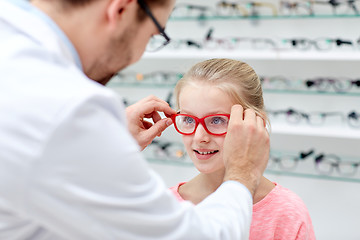 Image showing optician putting glasses to girl at optics store