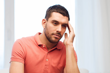 Image showing unhappy man suffering from headache at home