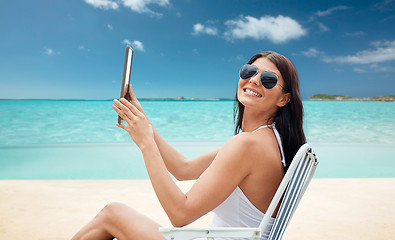 Image showing smiling woman with tablet pc sunbathing on beach