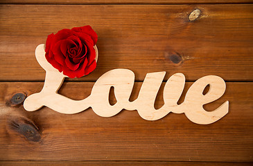 Image showing close up of word love cutout with red rose on wood