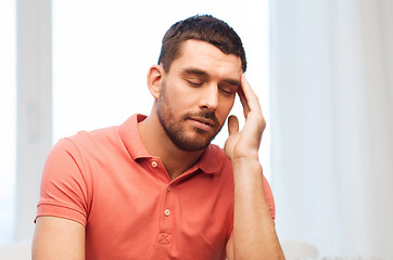 Image showing unhappy man suffering from headache at home