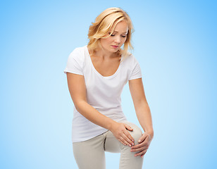 Image showing unhappy woman suffering from pain in leg