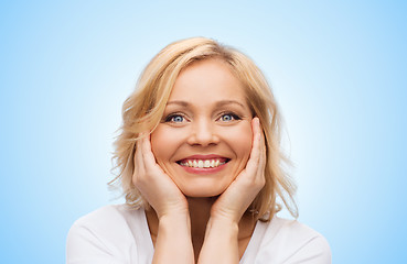 Image showing smiling woman in white t-shirt touching her face