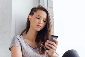 Image showing sad pretty teenage girl with smartphone texting