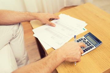 Image showing close up of man with papers and calculator at home