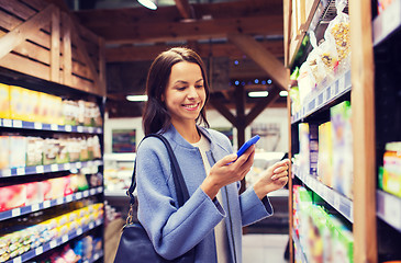 Image showing happy young woman with smartphone in market