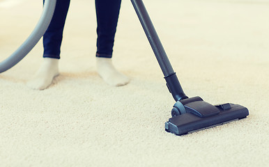 Image showing close up of woman legs with vacuum cleaner at home