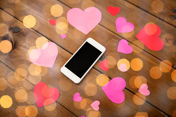 Image showing close up of smartphone and hearts on wood