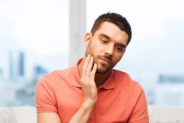 Image showing unhappy man suffering toothache at home