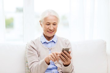 Image showing senior woman with smartphone texting at home