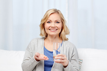 Image showing happy woman with medicine and water glass at home