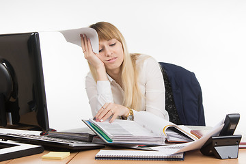 Image showing Frustrated and tired woman in the office leafing through a folder with papers