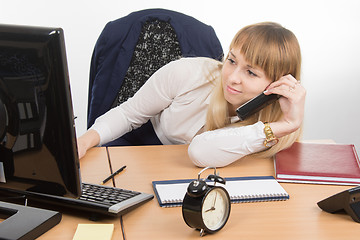 Image showing Tired office employee lying on the desk talking on the phone and looked at the screen