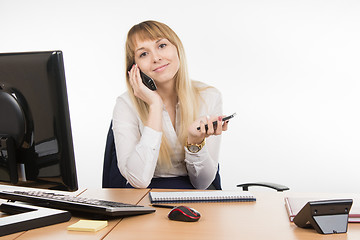 Image showing Happy secretary talking on the phone and working holding cell