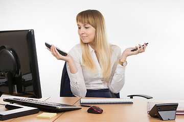 Image showing Secretary holding two phone rang and looked at work