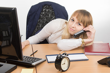 Image showing Tired office employee lying on the desk talking on the phone and looked at the frame