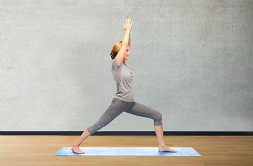 Image showing woman making yoga warrior pose on mat